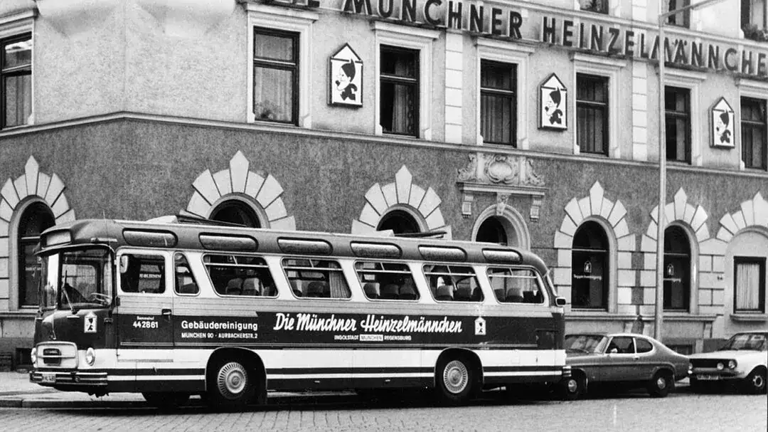 Alter Bus vor historischem Gebäude in München, schwarz-weiß Bild.