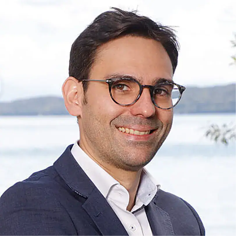 Markus Mayr in Businesskleidung vor Wasserlandschaft.