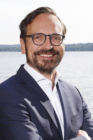 Professioneller Geschäftsmann trägt Anzug und Brille am Wasser.