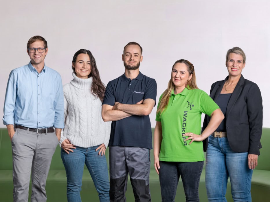 Fünf Mitarbeiter der Wackler Service Group vor neutralem Hintergrund.