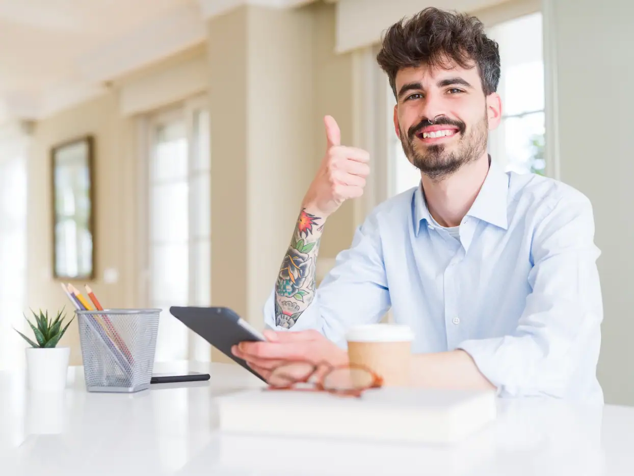 Mann mit Smartphone und Daumen hoch im Büro.