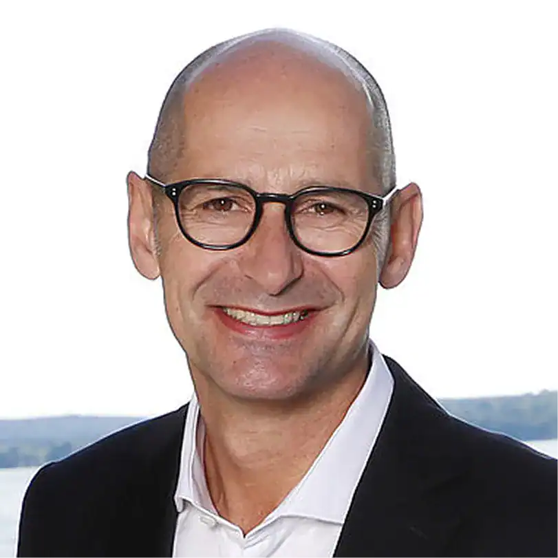 Jens Riemann in Businesskleidung vor Wasserlandschaft.