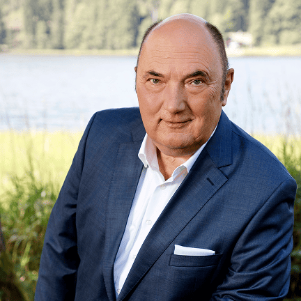 Geschäftsmann in Anzug vor Wasser und Natur im Hintergrund.