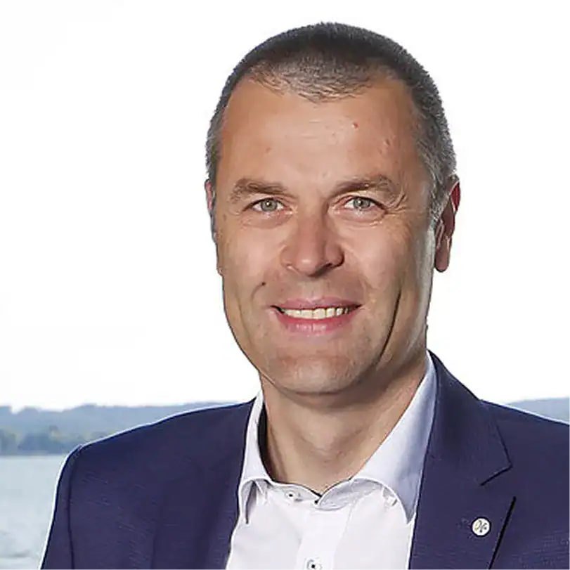 Jens Riemann in Businesskleidung vor Wasserlandschaft.