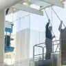 Reinigungskraft bei der Fassadenreinigung eines Gebäudes mit Reinigungsroboter.