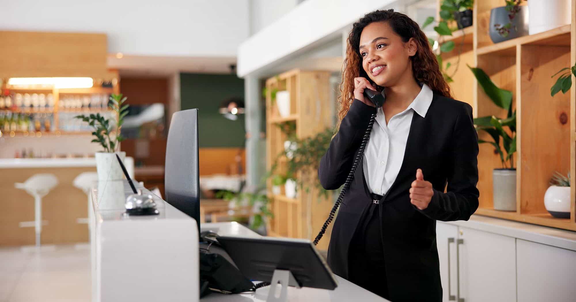 Frau am Empfang mit Telefon und Computer im modernen Büro.