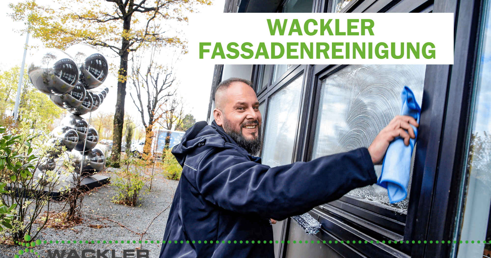 Mitarbeiter reinigt eine Glasfassade mit einem Tuch.