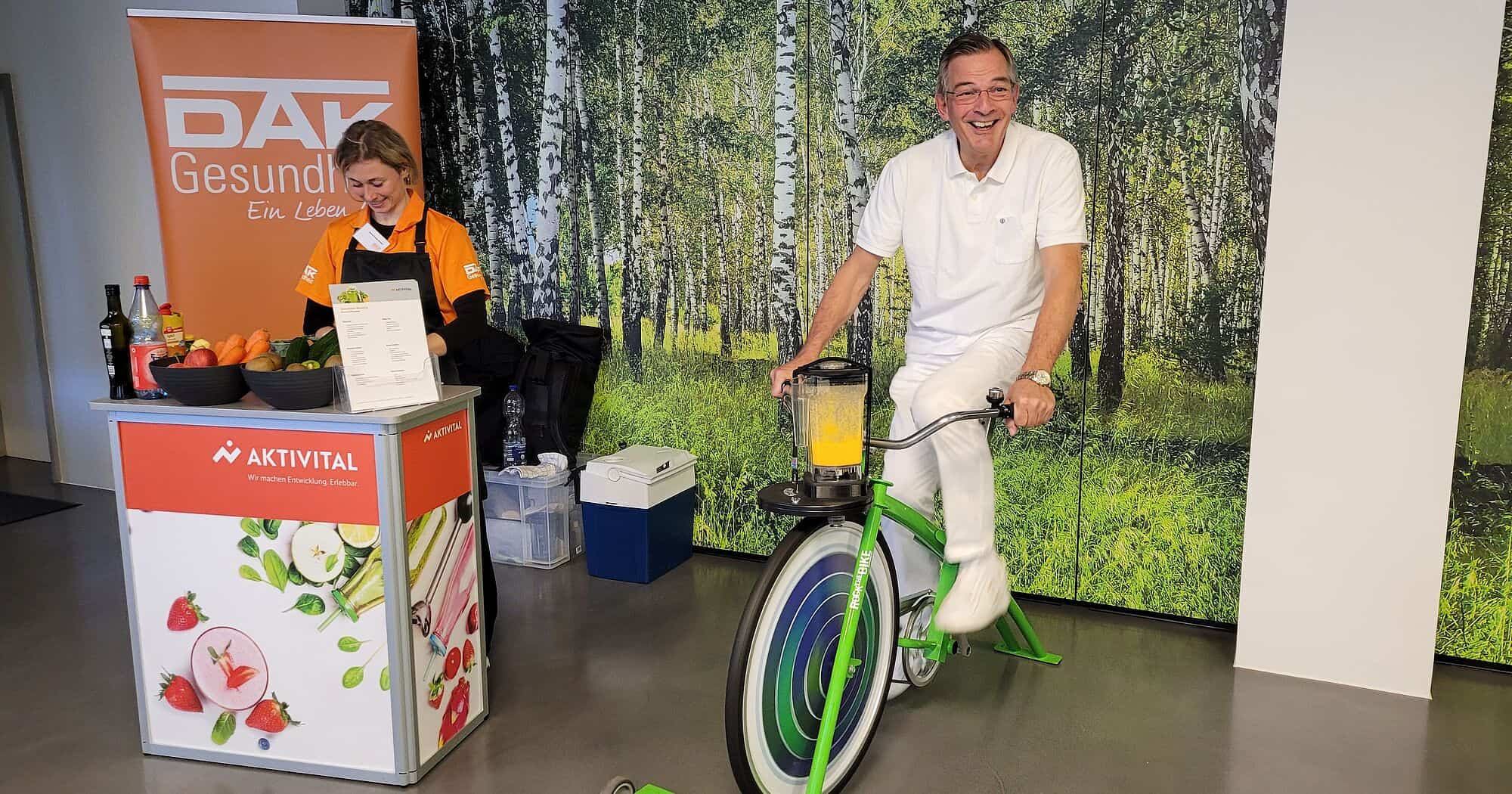 Mitarbeiter bei Gesundheitstag mit Fahrrad und Infostand.