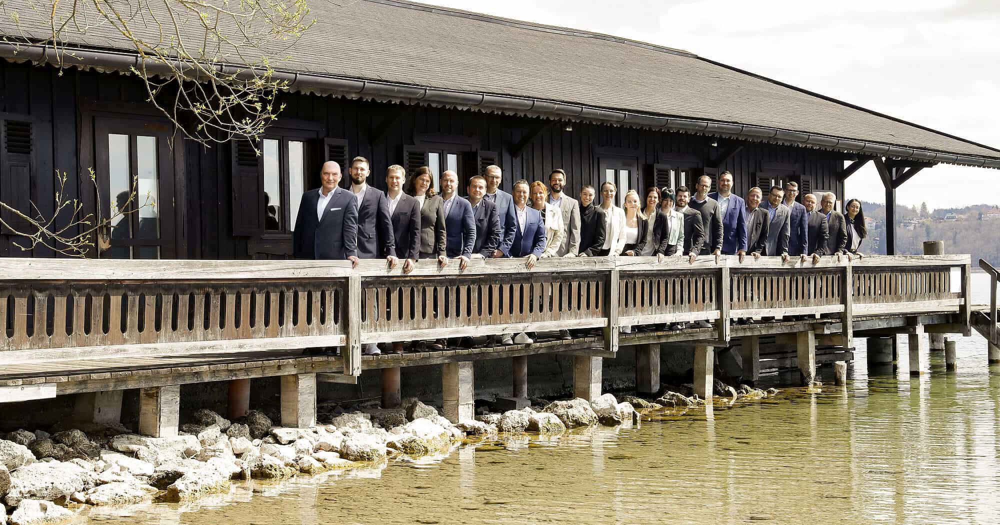 Geschäftsleute stehen auf einer Holzterrasse am Wasser.