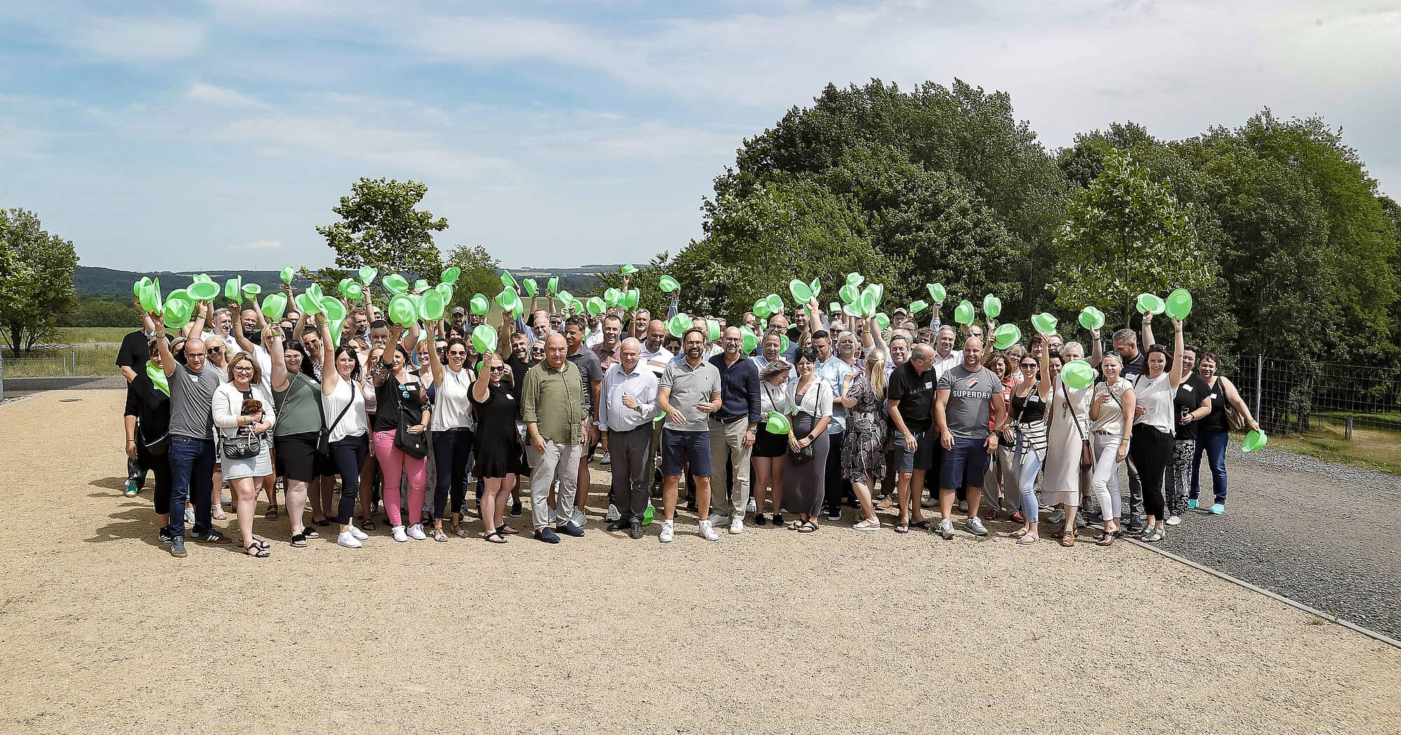 Gruppenfoto beim Sommerfest mit Ballons und Natur im Hintergrund.