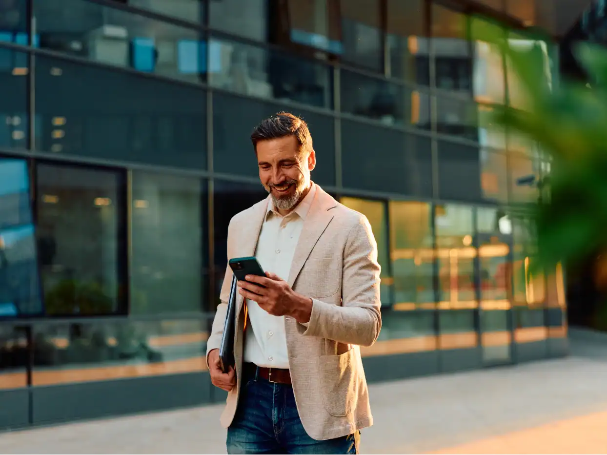 Geschäftsmann nutzt Smartphone vor moderner Bürofassade.