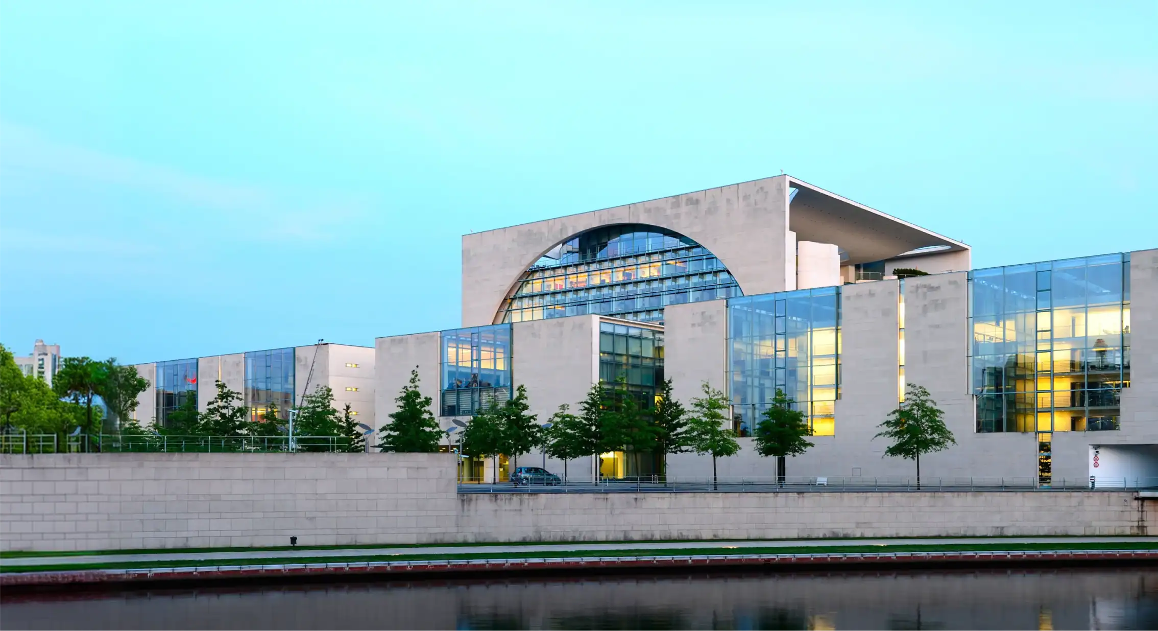 Zeitgenössisches Gebäude mit Glasfassade und Wasser im Vordergrund.