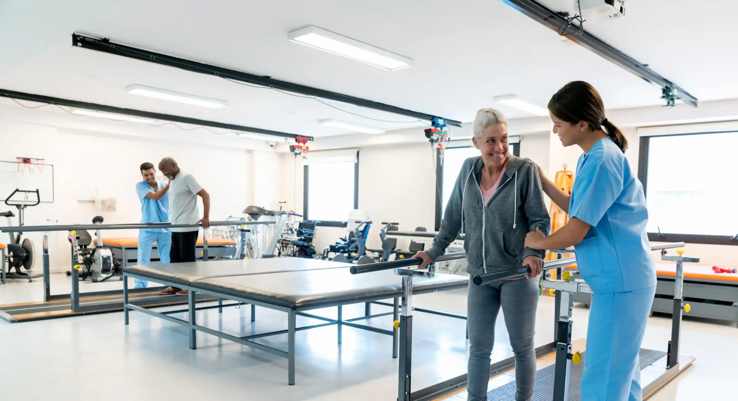 Pflegekraft spricht mit älterer Patientin im Rehabilitationszentrum.