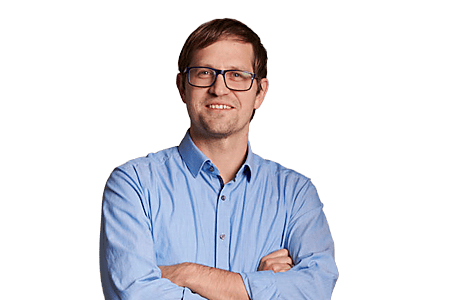 Mann in Brille und blauer Hemd mit verschränkten Armen.