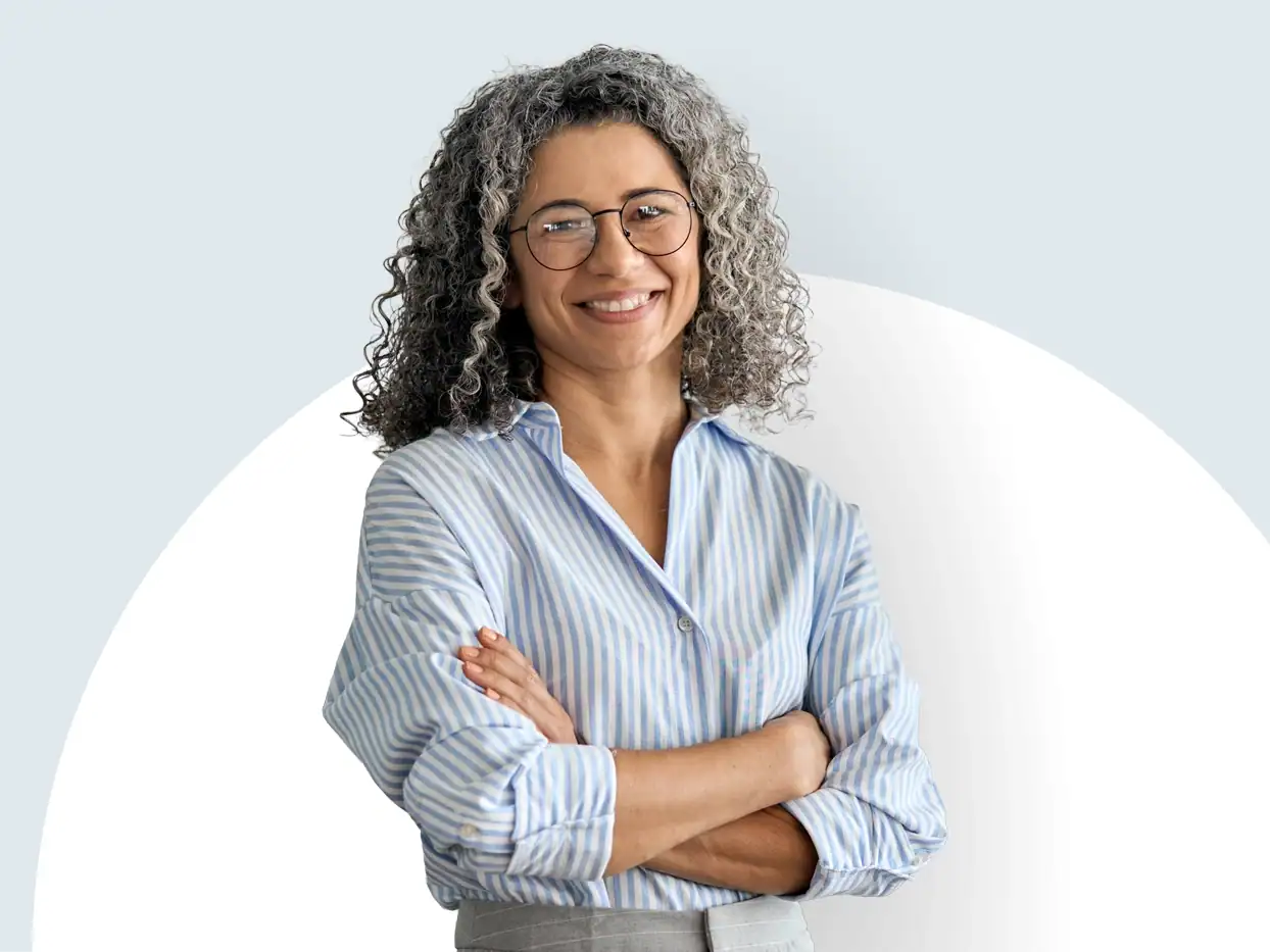 Frau mit Brille und lockigem Haar lächelt, trägt blauen Hemd.