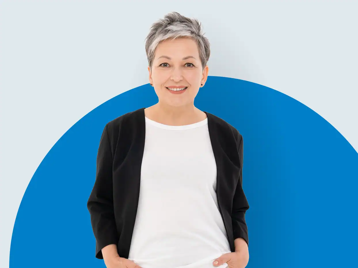 Lächelnde Frau in Businesskleidung vor blauem Hintergrund.