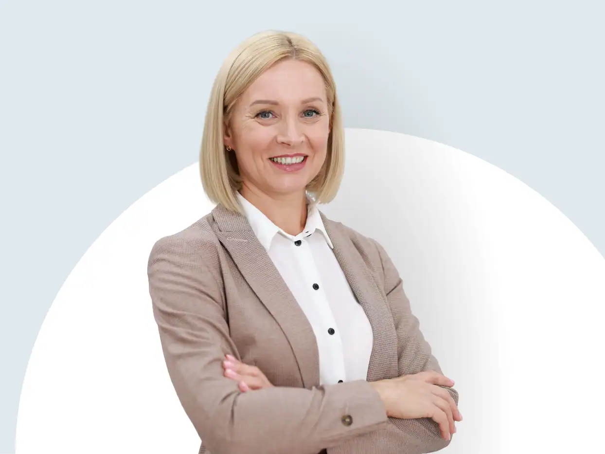 Frau in Businesskleidung mit verschränkten Armen vor weißem Hintergrund.