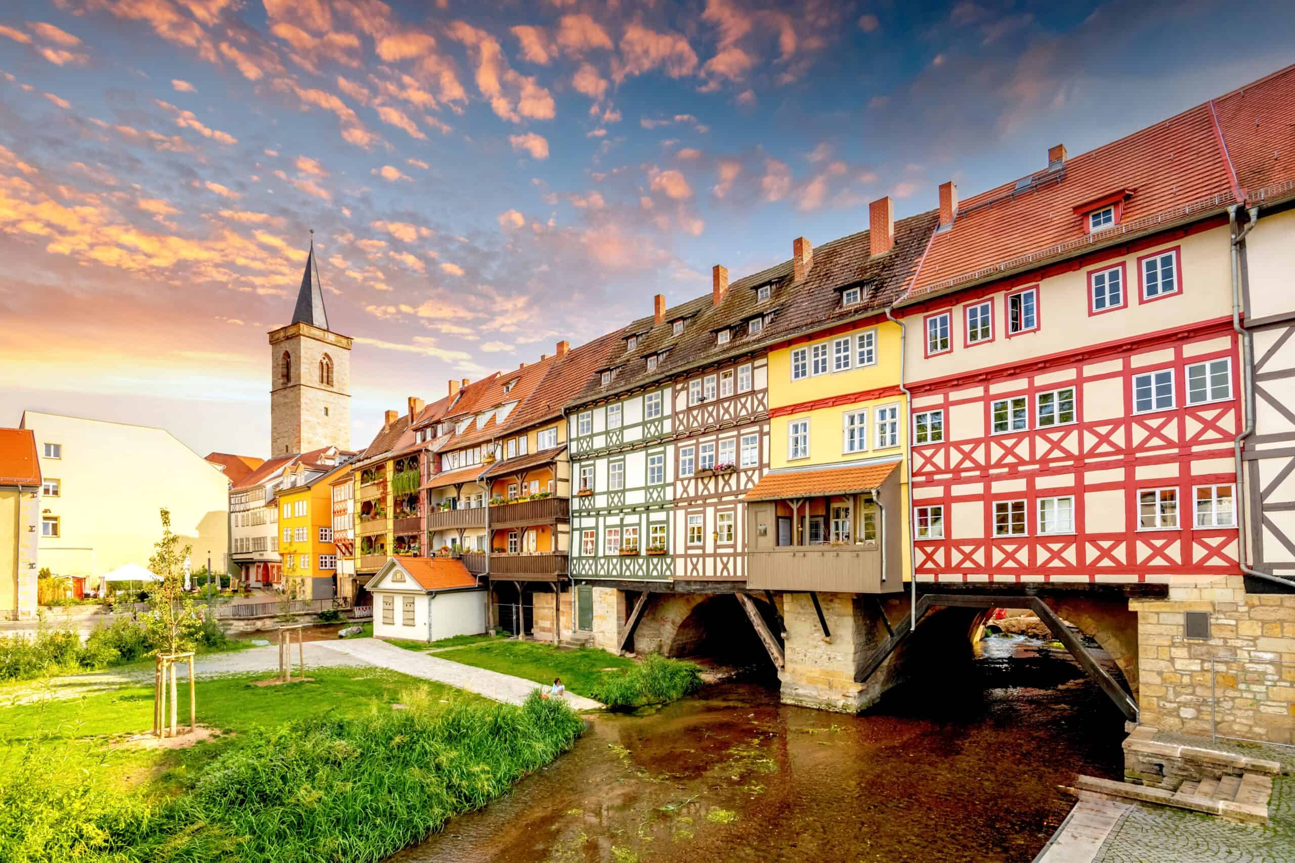 Bunte Fachwerkhäuser über einer kleinen Brücke in Deutschland bei Sonnenuntergang.