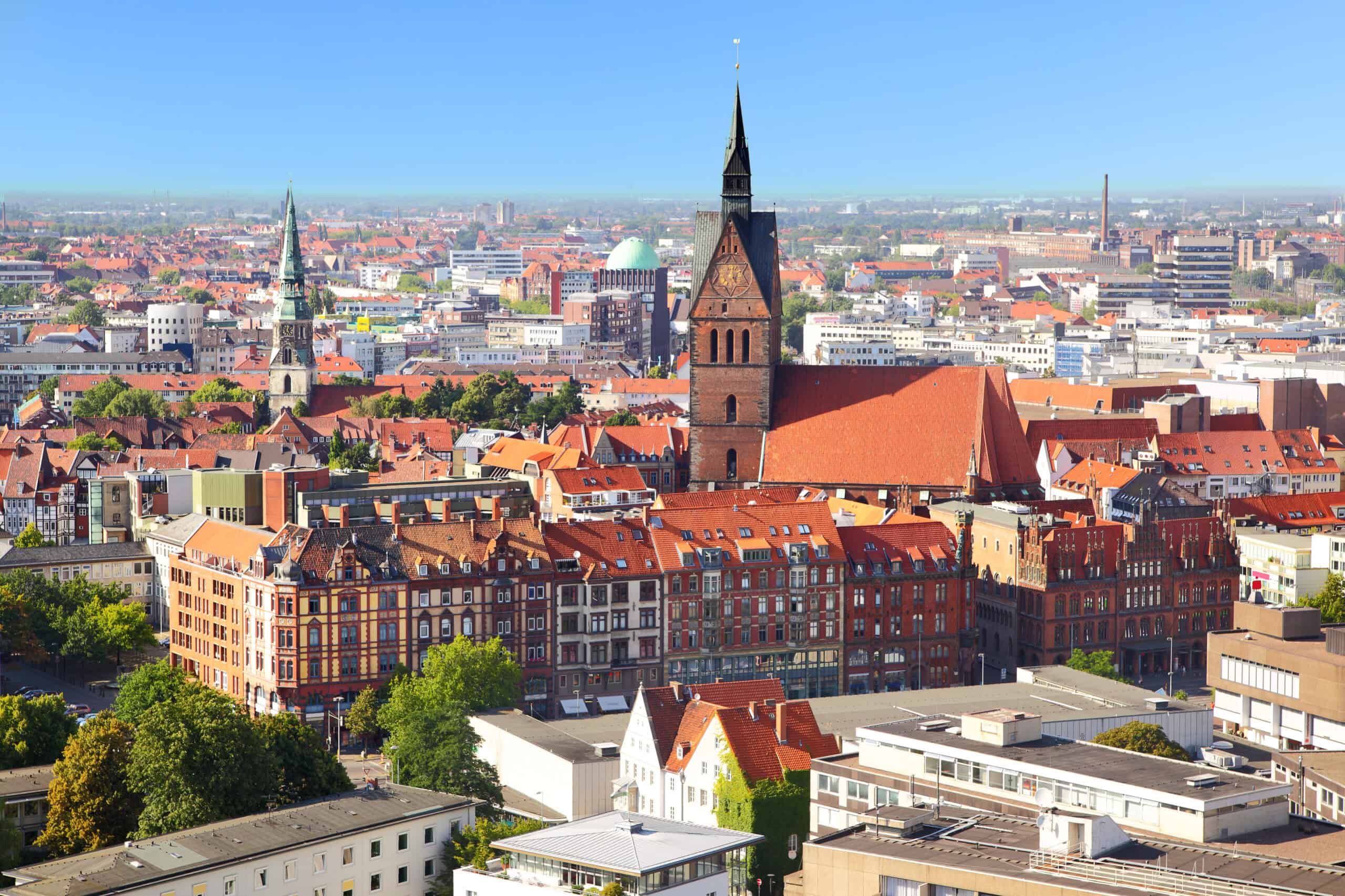 Panoramablick auf die Stadt mit Kirchtürmen und roten Dächern.