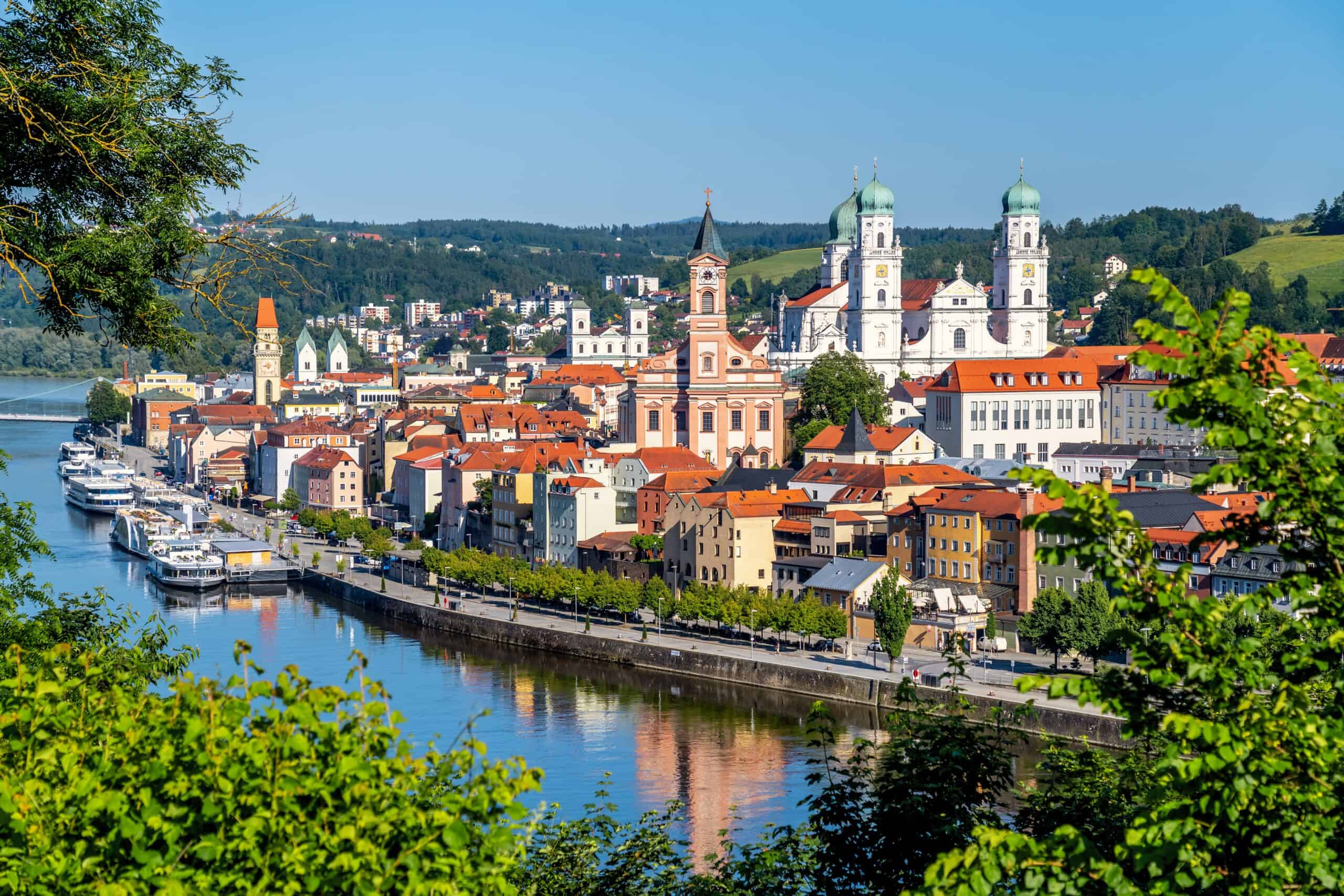Panoramablick auf Passau mit Fluss, Kirchen und Gebäuden bei Sonnenschein.