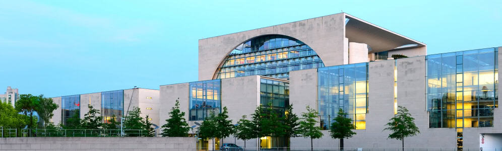 Zeitgenössisches Bürogebäude mit Glasfassade und grüner Umgebung.